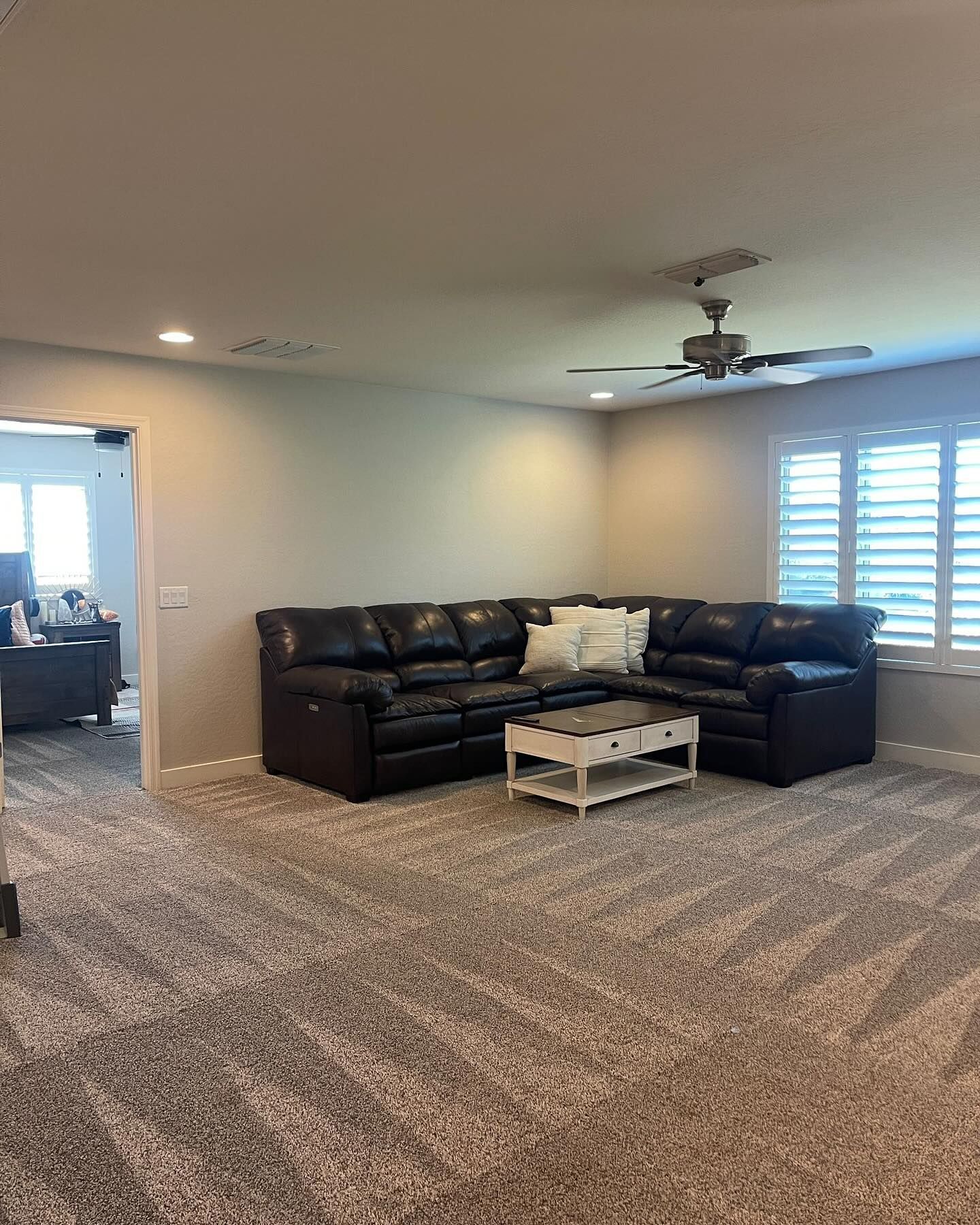 A living room with a couch , coffee table , and ceiling fan.