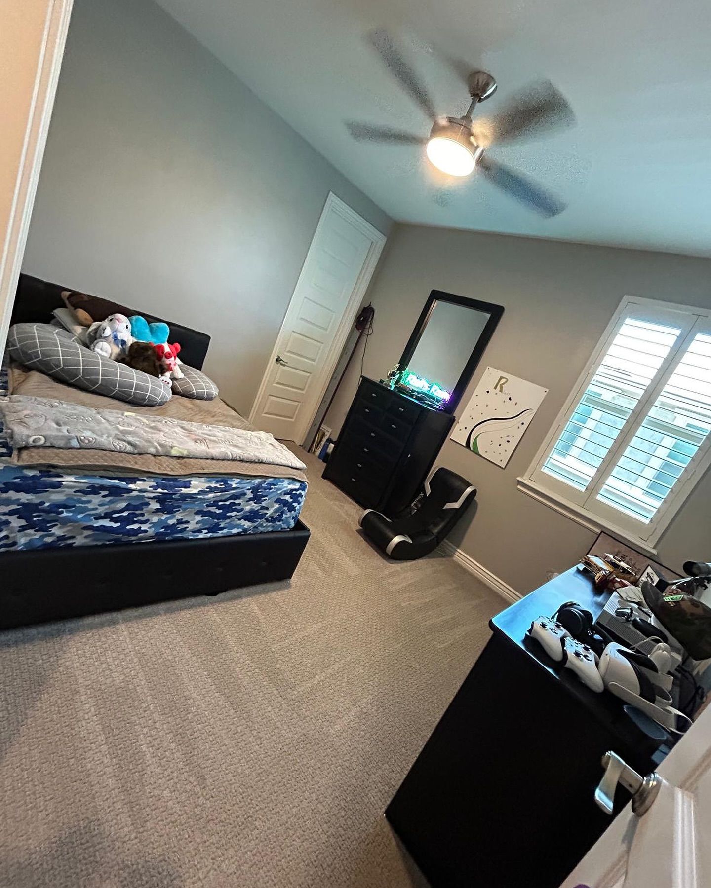 A bedroom with a bed , dresser , mirror and ceiling fan.