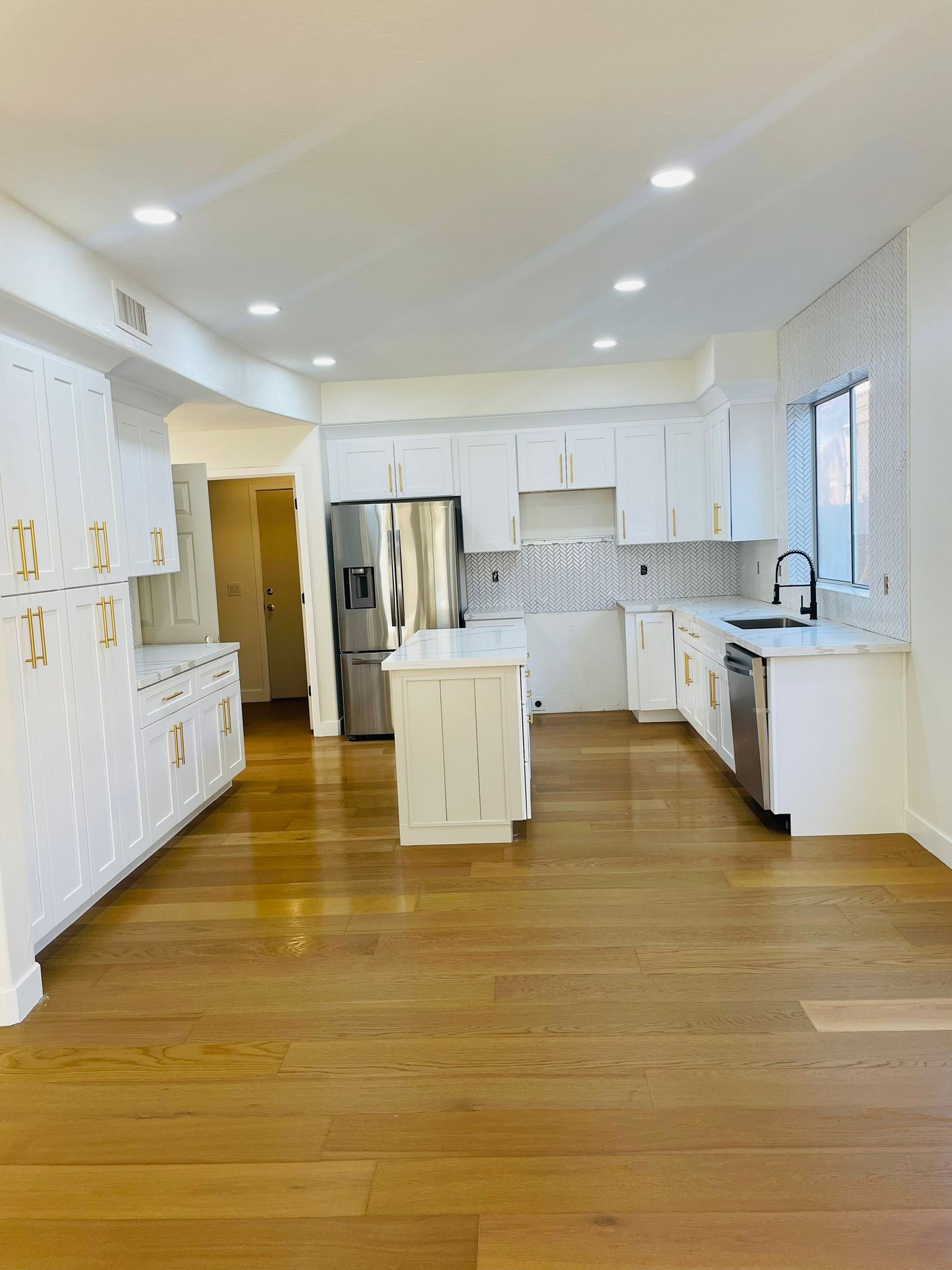 A kitchen with white cabinets , stainless steel appliances , and hardwood floors.