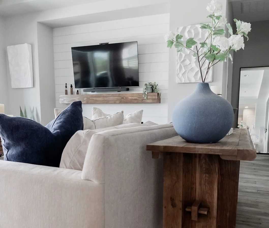 A living room with a couch and a vase of flowers on a wooden table.