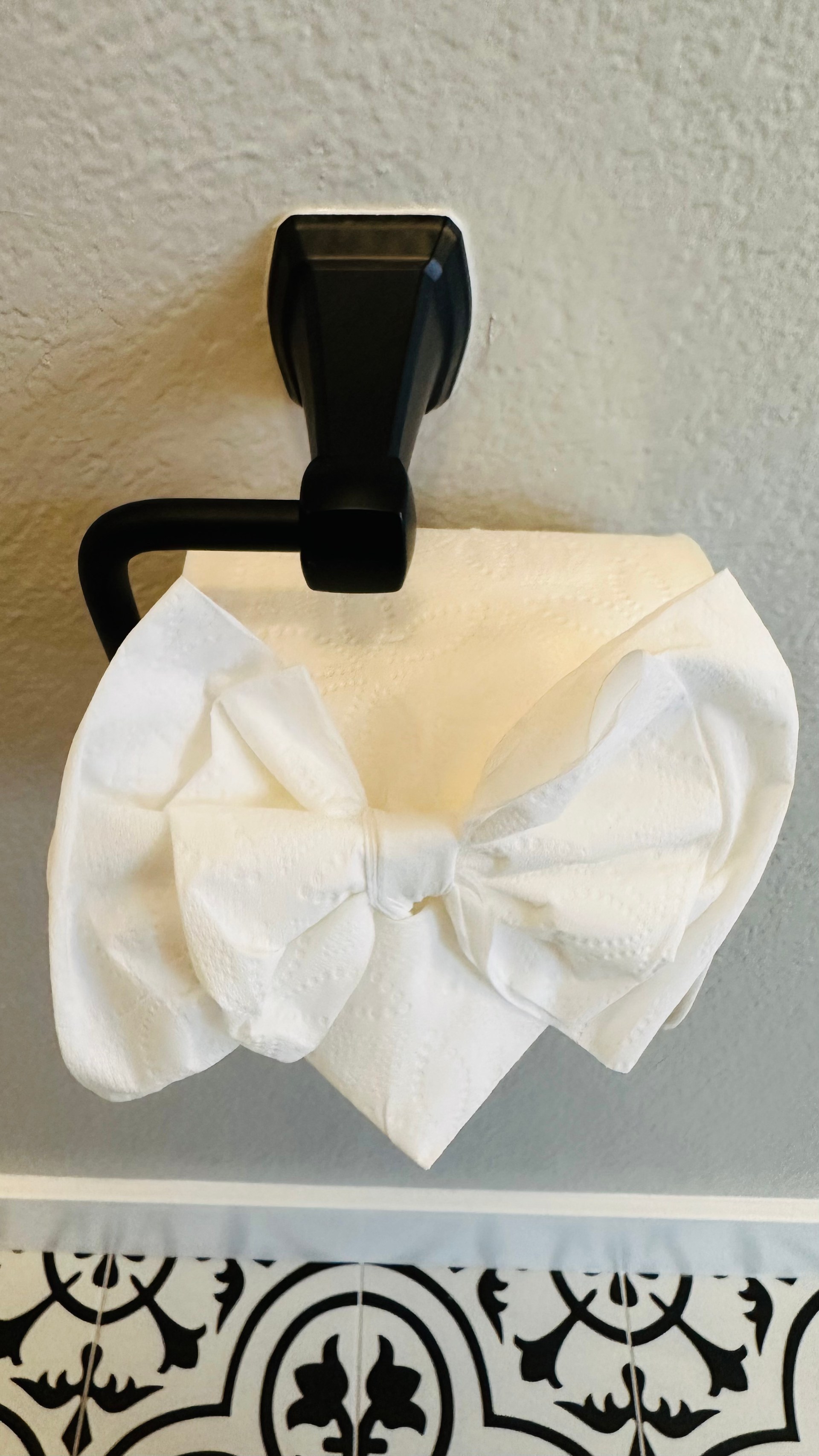A toilet paper holder with a white bow on it