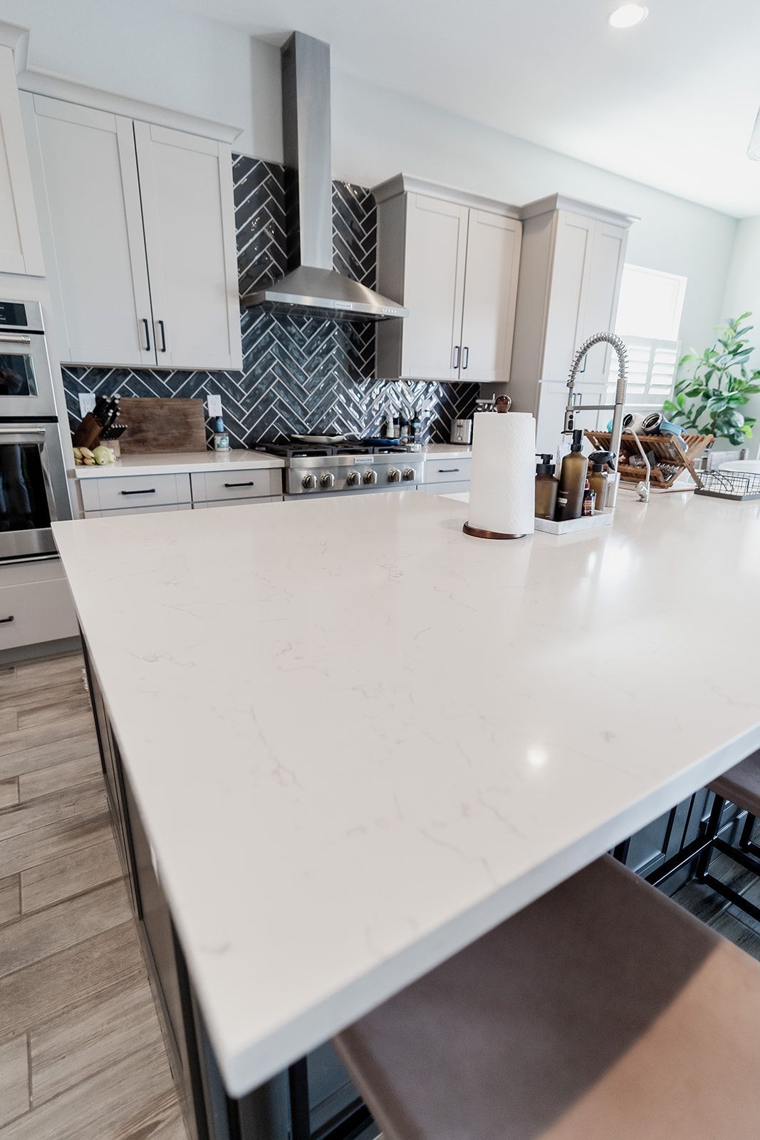 A kitchen with white cabinets , stainless steel appliances , and a large island.