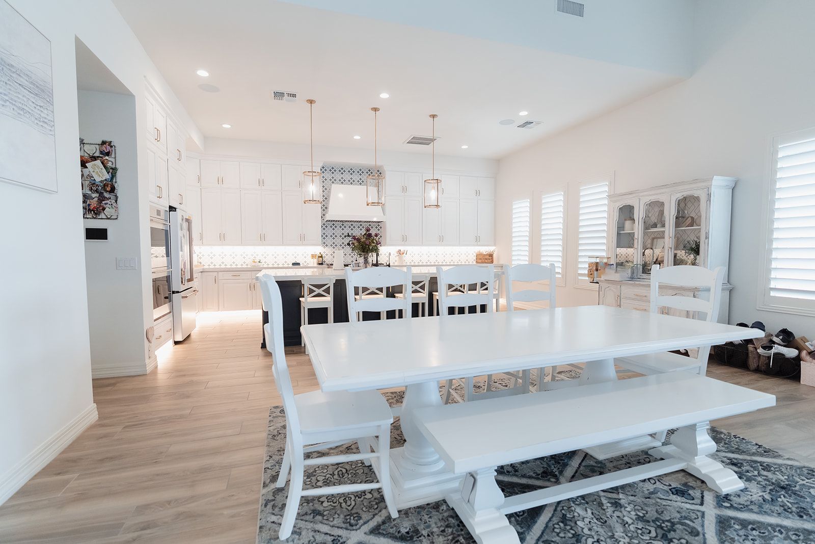 A dining room with a white table and chairs and a bench.