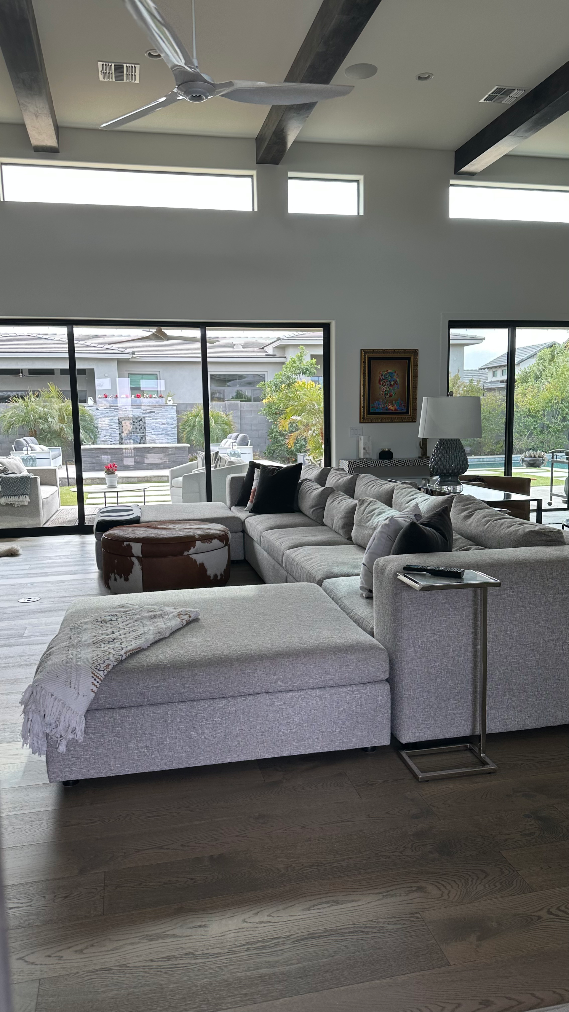 A living room with a large sectional couch and a ceiling fan.