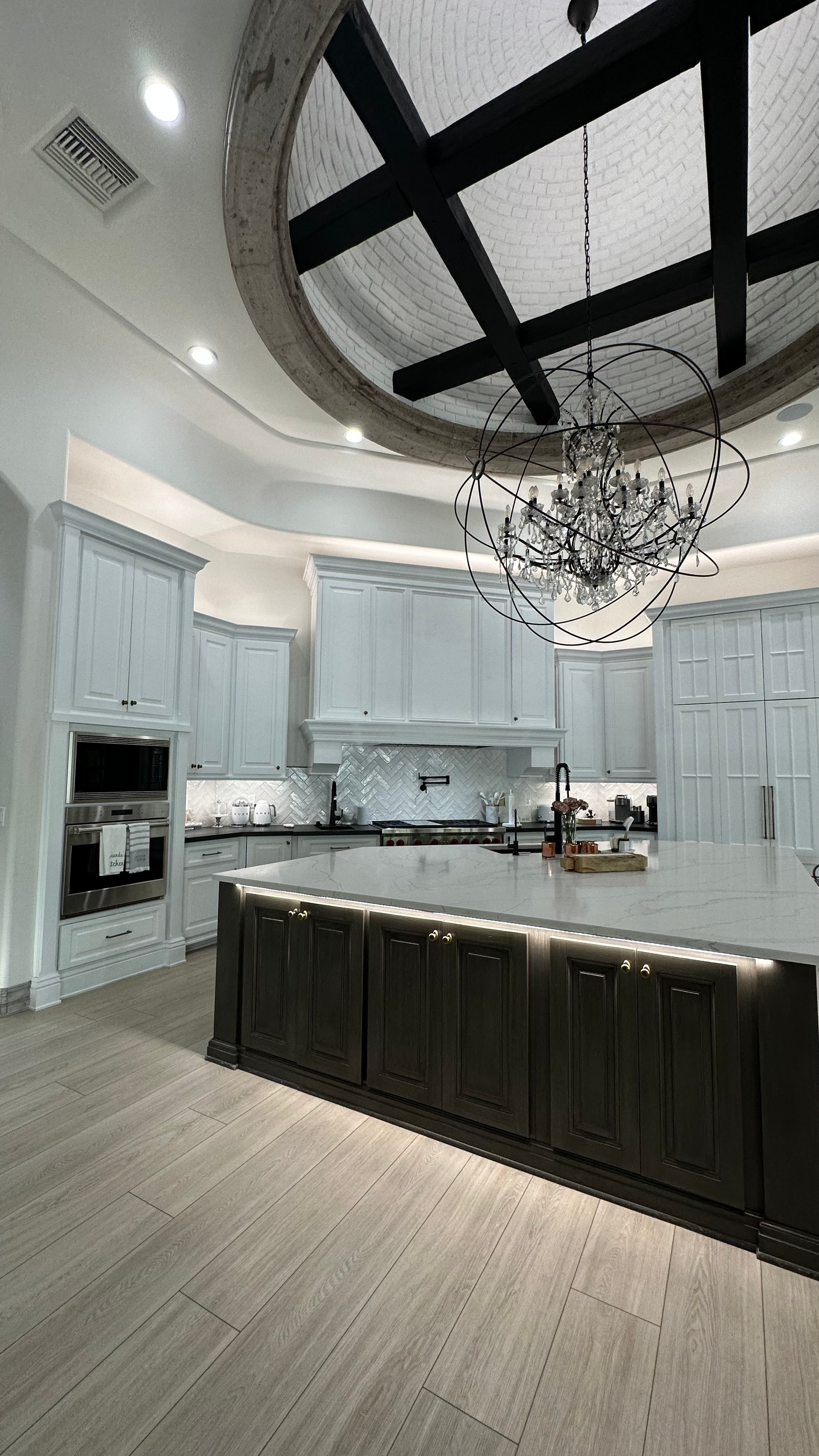 A kitchen with a large island and a chandelier hanging from the ceiling.