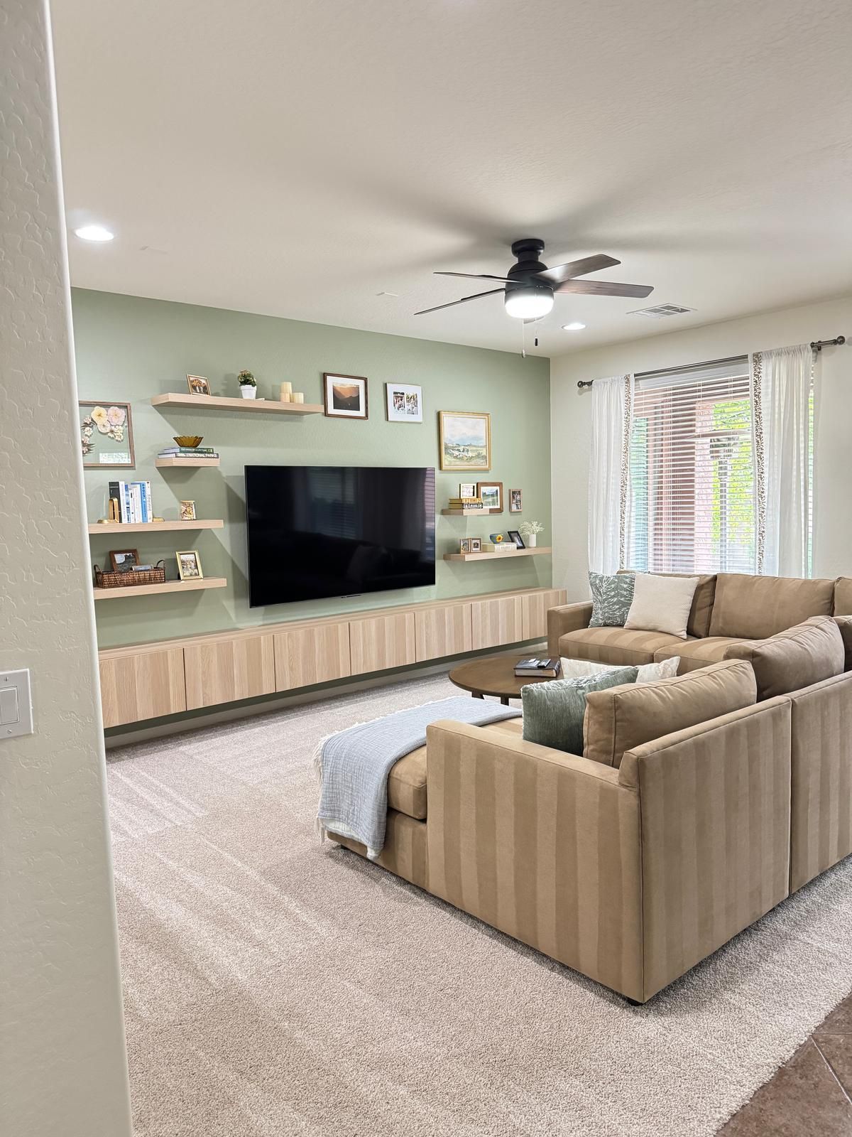 A living room with a couch , television , and ceiling fan.