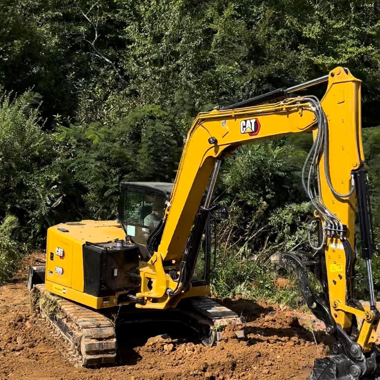 A yellow excavator is sitting in the middle of a dirt field.