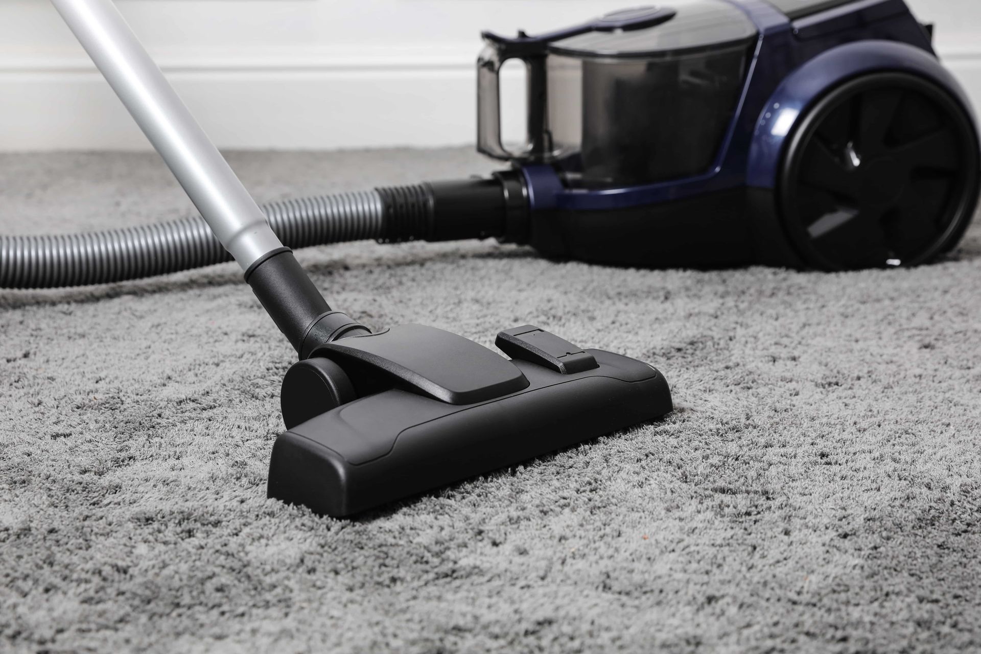A vacuum cleaner is being used to clean a carpet.