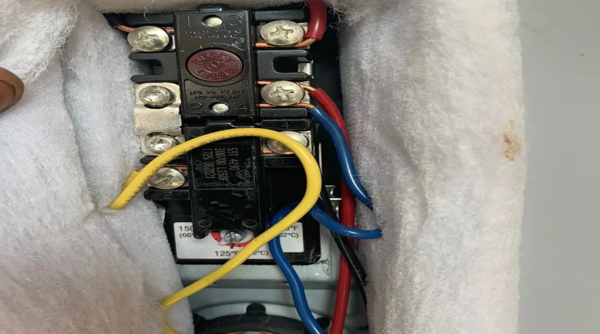 Electrical component with red button and wires: red, blue, and yellow, housed in white insulation.