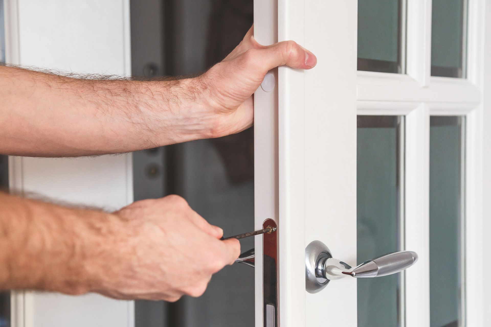 A man is fixing a door with a screwdriver.