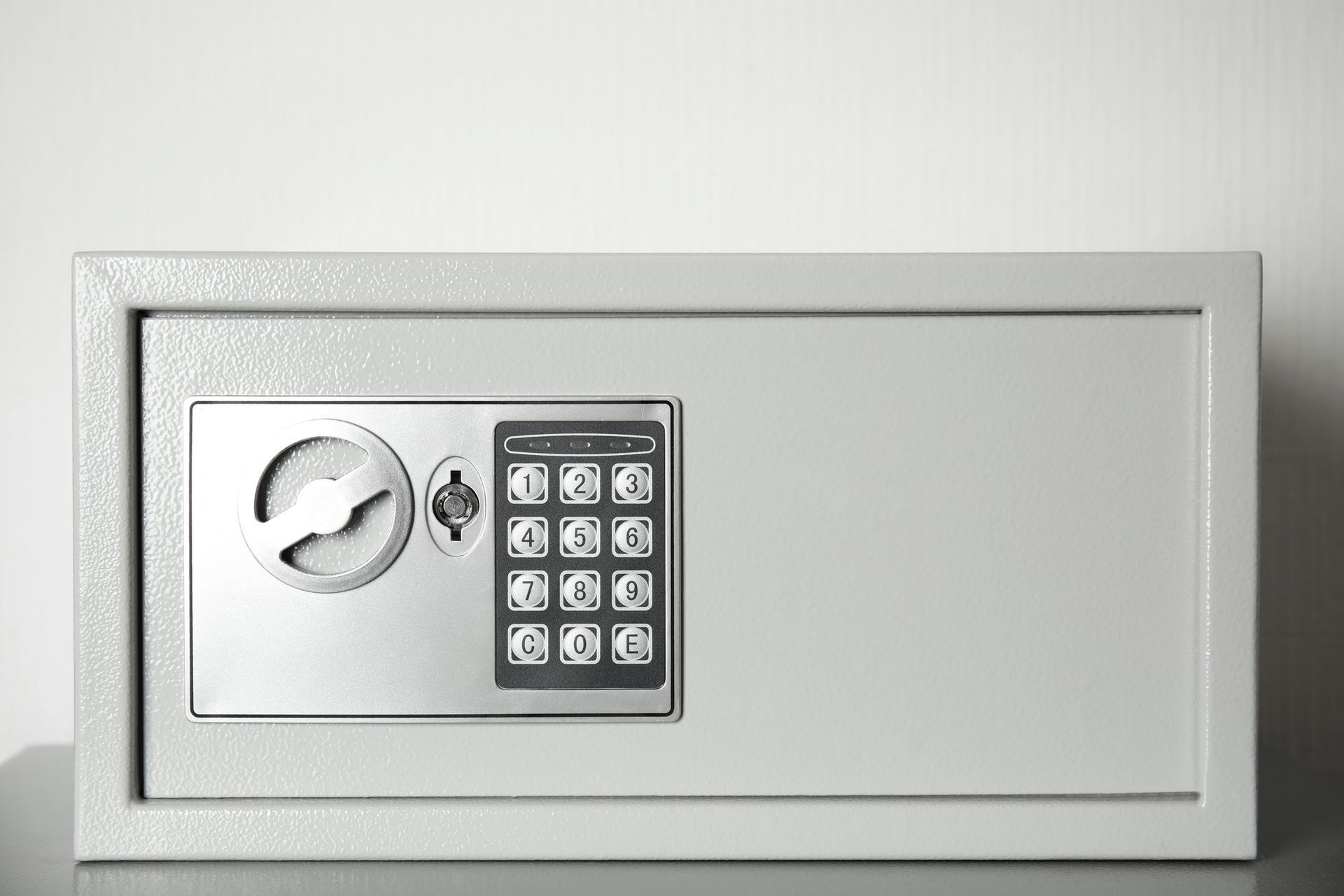 A silver safe with a digital keypad is sitting on a table.