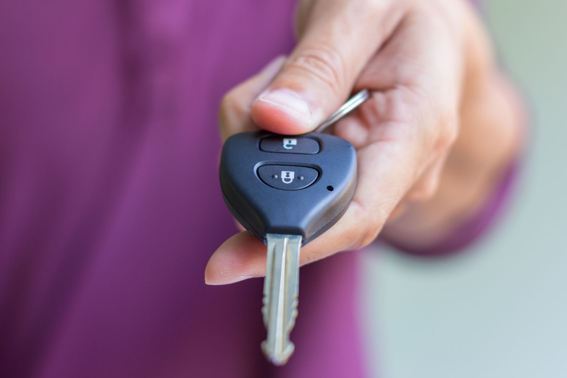 A person is holding a car key in their hand.