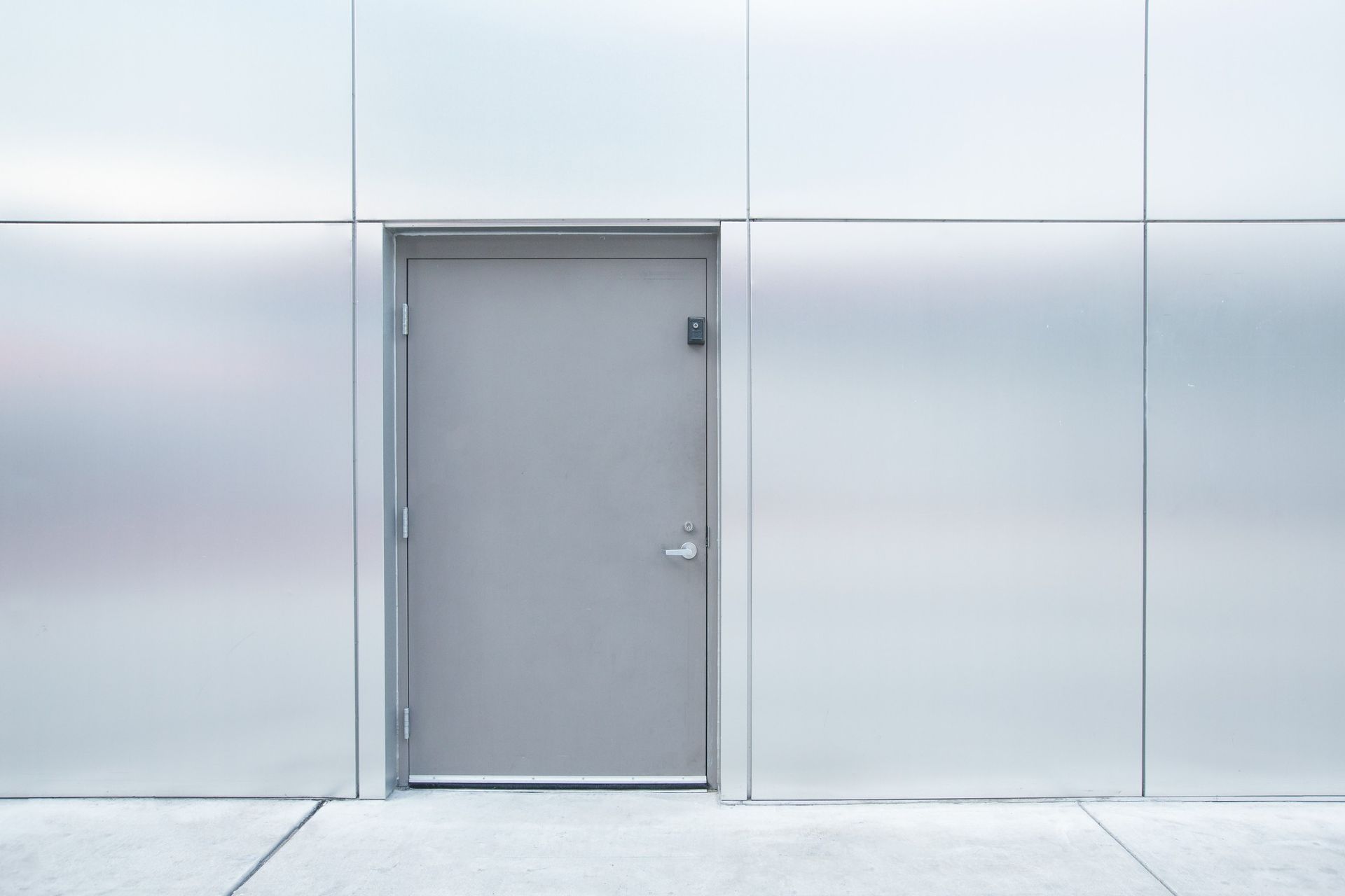A gray door is sitting in front of a stainless steel wall.