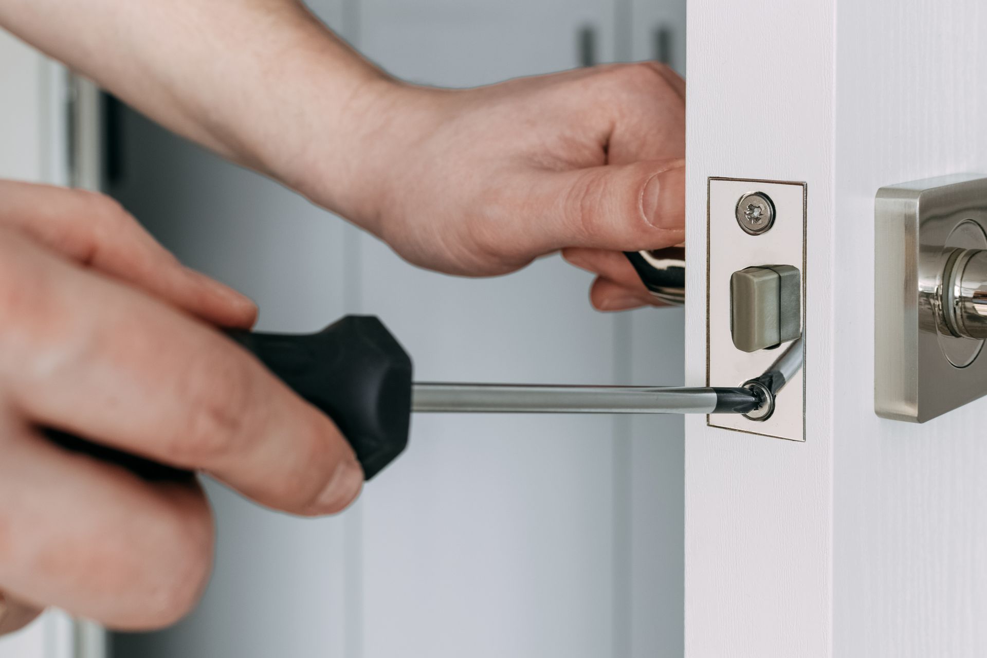 A person is fixing a door with a screwdriver.