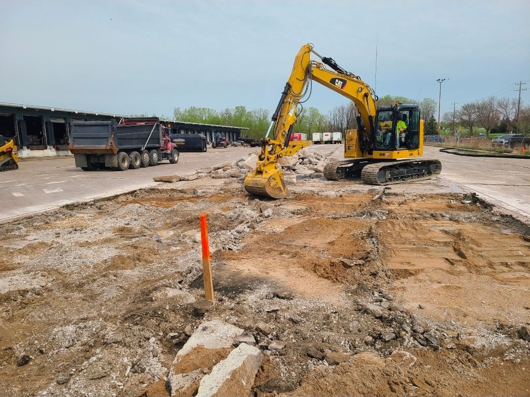 A man is driving an excavator in a dirt field.