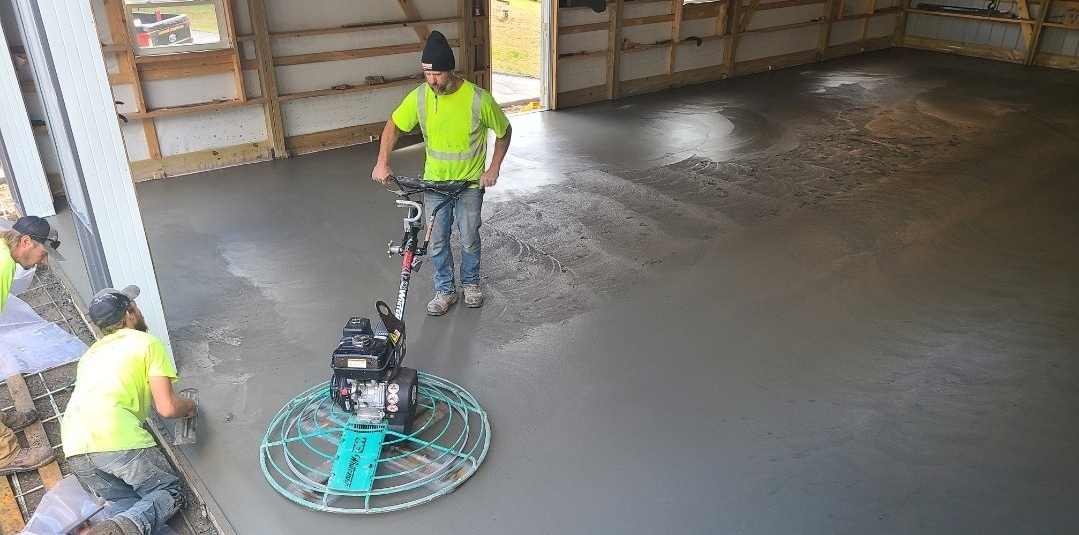 A group of construction workers are working on a concrete floor.