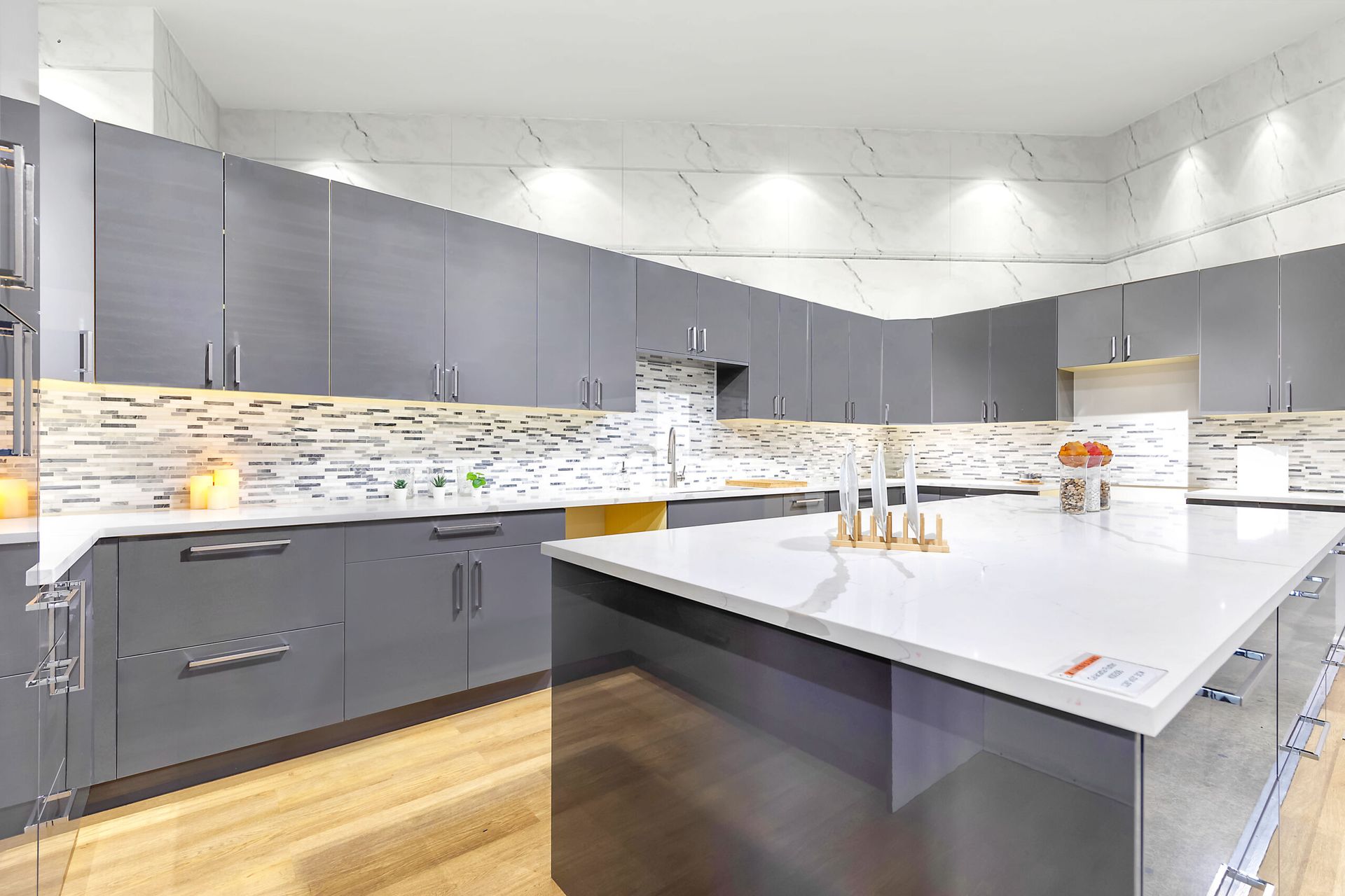 Modern kitchen with gray cabinets, white countertops, and a large island.