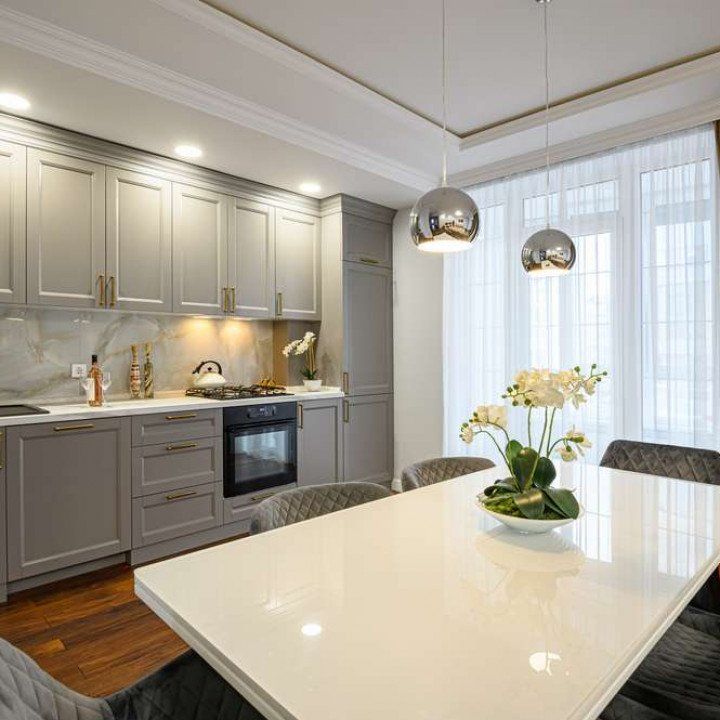 Gray kitchen with marble backsplash, white table, and silver pendant lights.