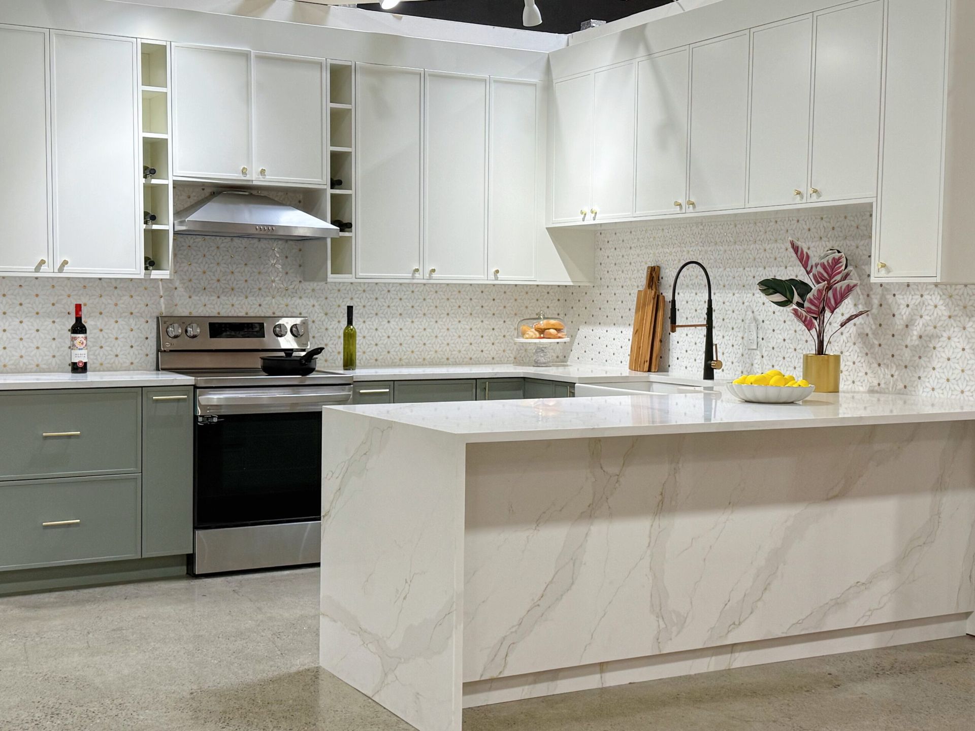 Modern kitchen with white and green cabinets, stainless steel appliances, and a marble island.