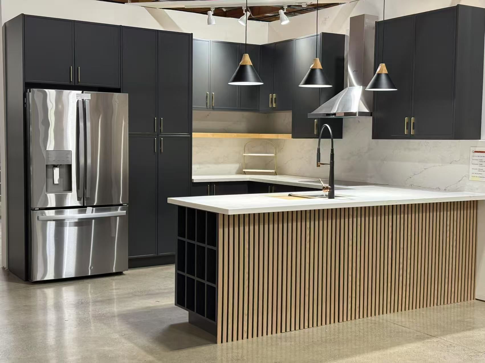 Modern kitchen with dark gray cabinets, stainless steel appliances, and a white countertop island.