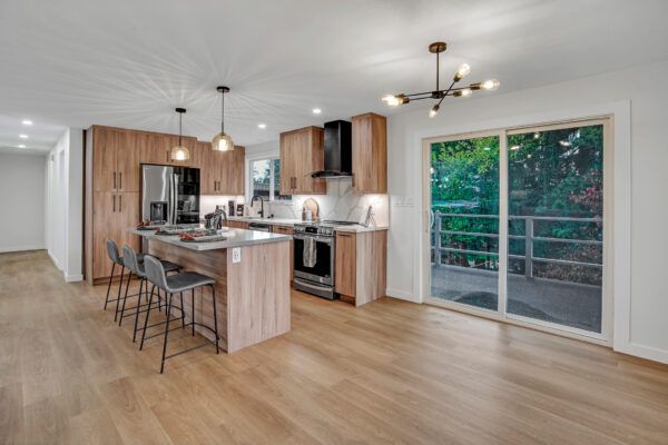 Modern kitchen with wood cabinets, island with stools, and sliding glass door to a balcony.