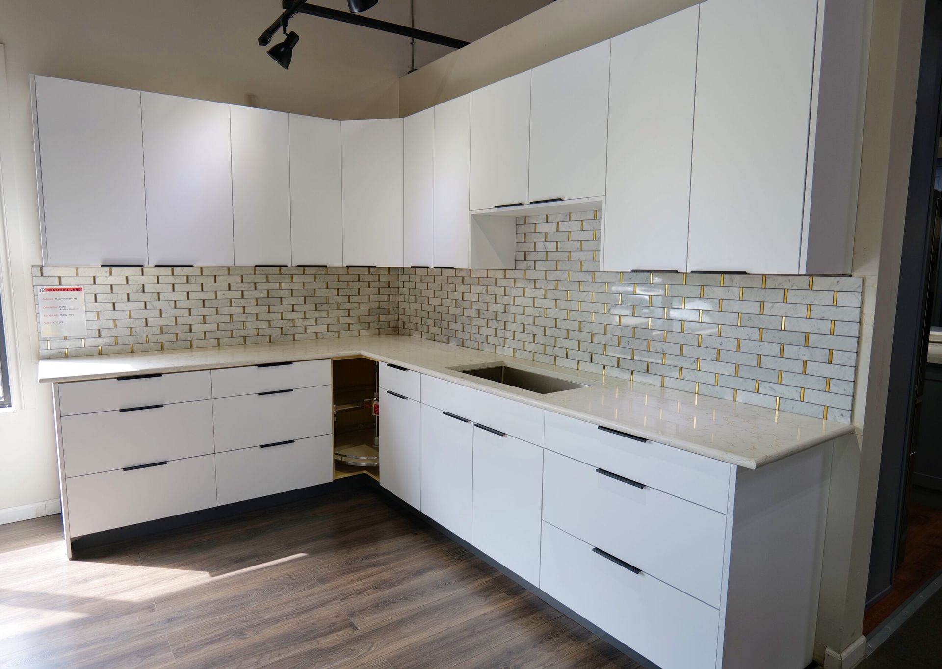 White kitchen cabinets and countertops with tile backsplash, empty.