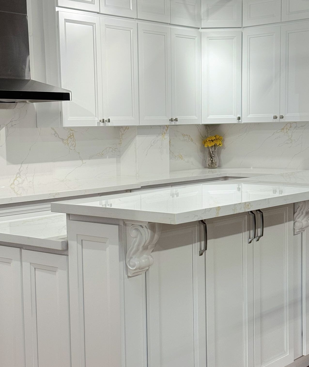 White kitchen cabinets and countertops with a range hood and small island.