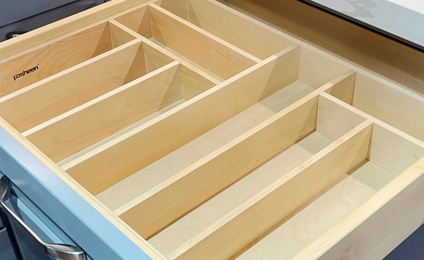 Open kitchen drawer with wooden dividers for organizing utensils.