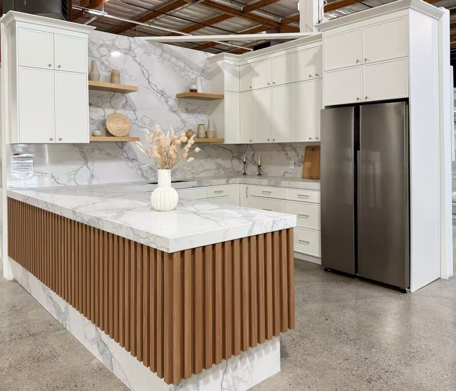 Modern kitchen with white cabinets, marble backsplash, brown island, and stainless steel refrigerator.