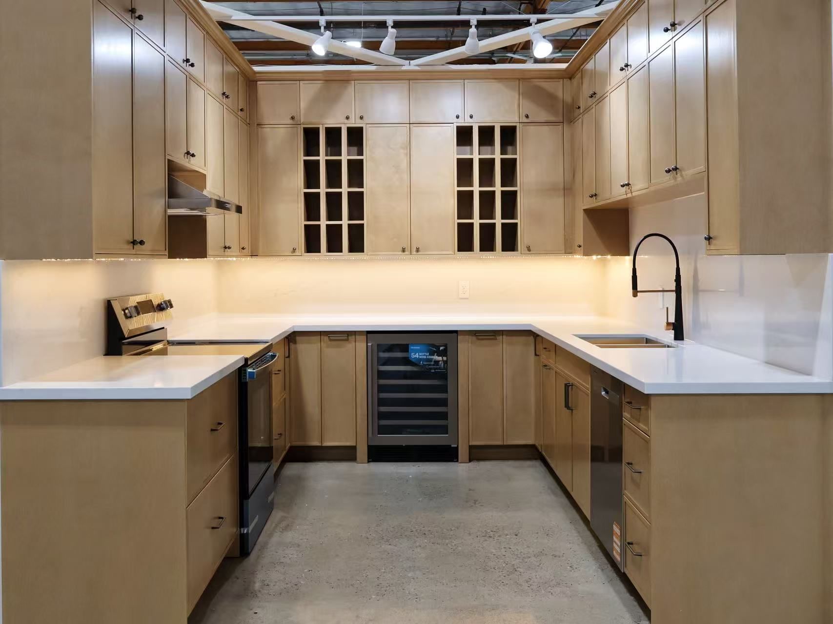U-shaped kitchen with light wood cabinets, white countertops, and stainless steel appliances.