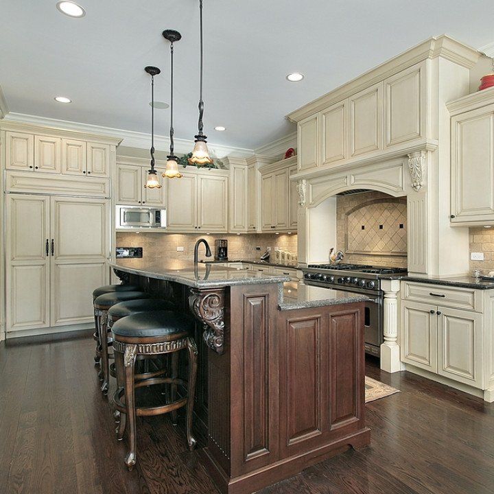 Cream-colored kitchen with dark wood island, granite countertops, and pendant lights.