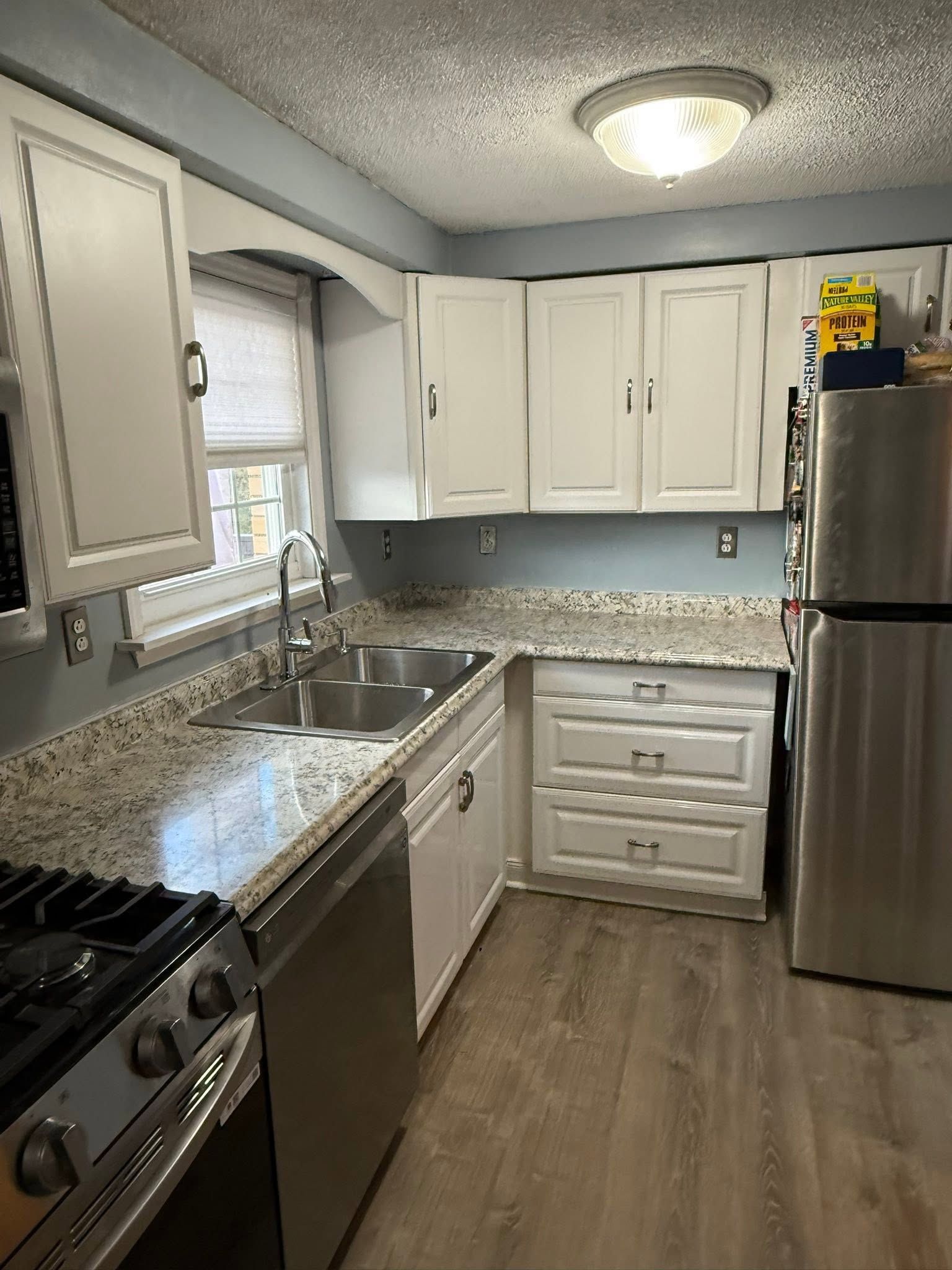 Small modern kitchen with white cabinets, stainless steel appliances, and gray countertops.