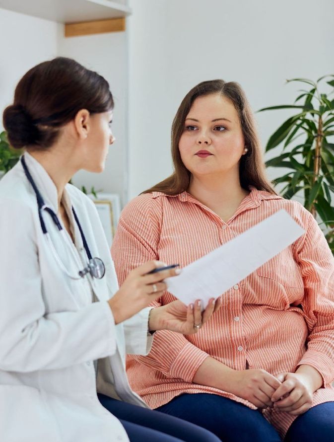 A doctor is talking to a patient who is holding a piece of paper.