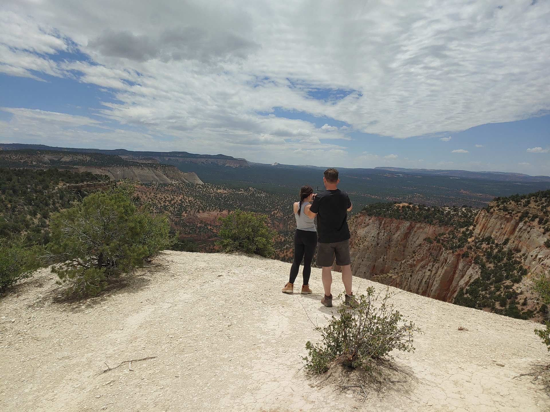 A man and a woman standing on top of a hill overlooking a valley