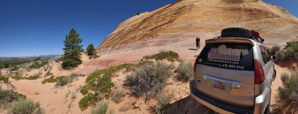 A car is parked on a dirt road next to a mountain.