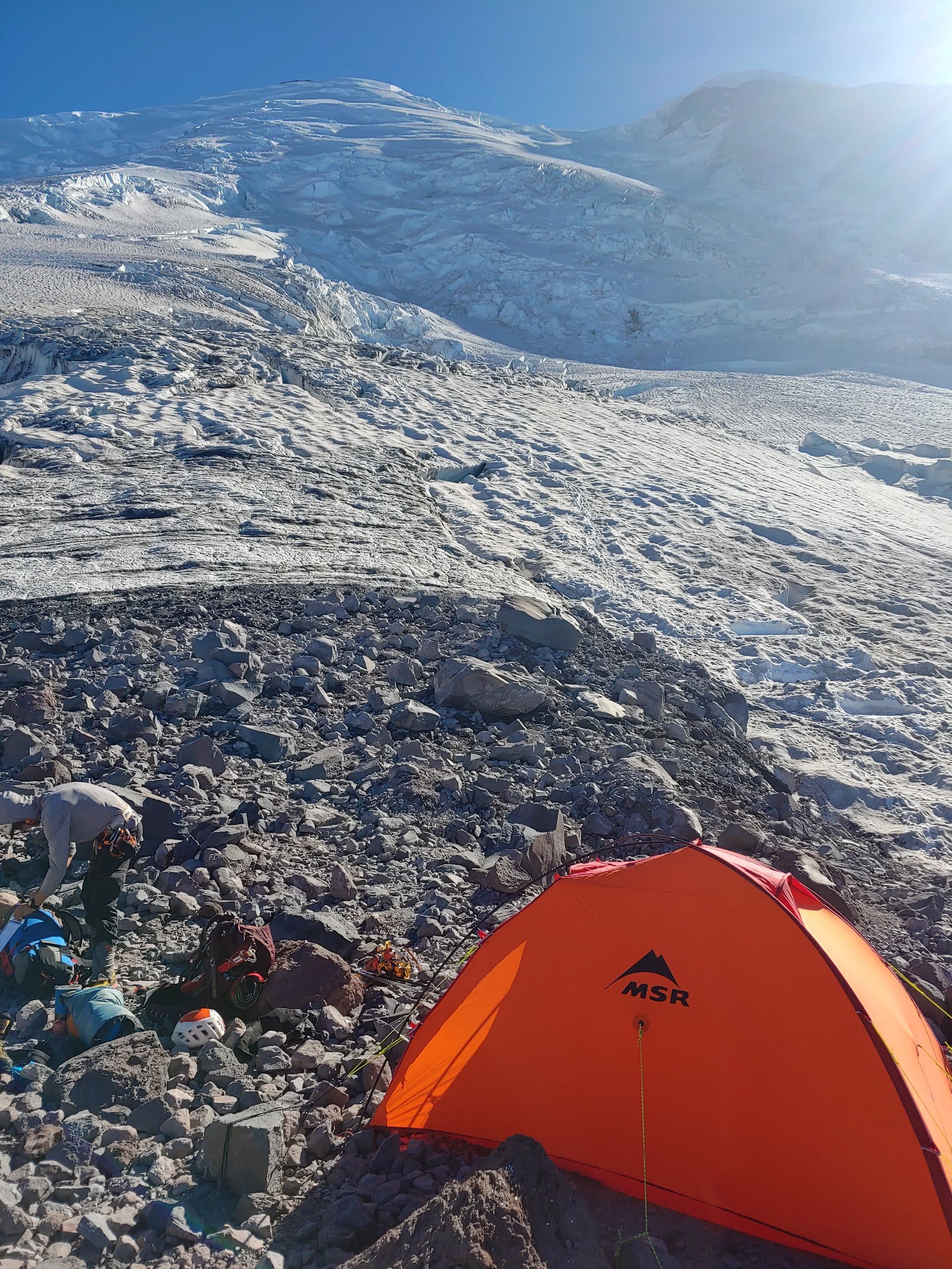 An orange tent set up along a mountain's side