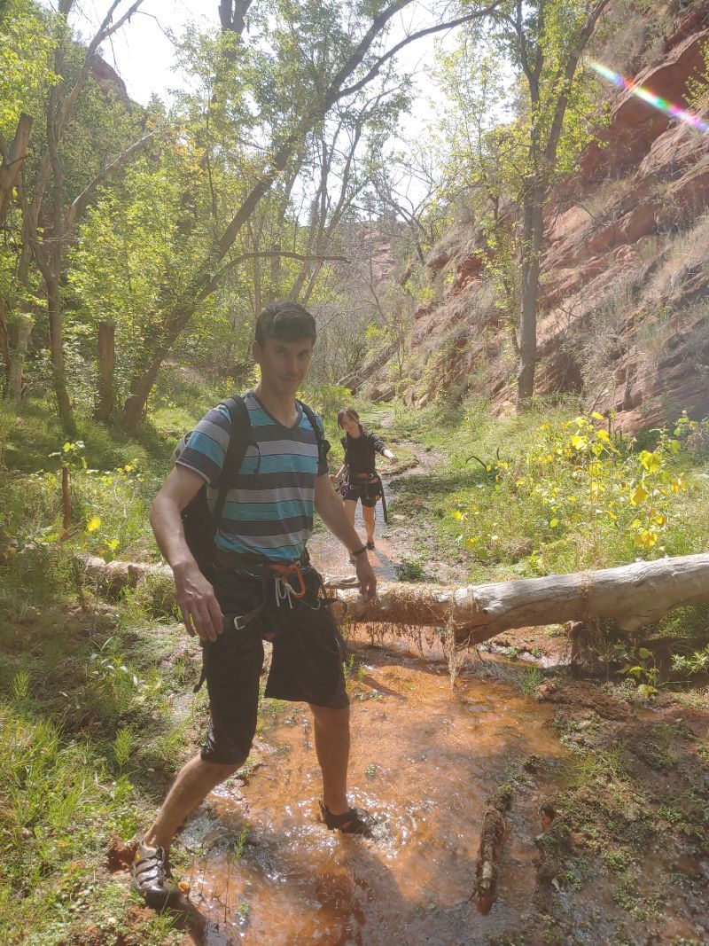 A man in a striped shirt is walking through a stream