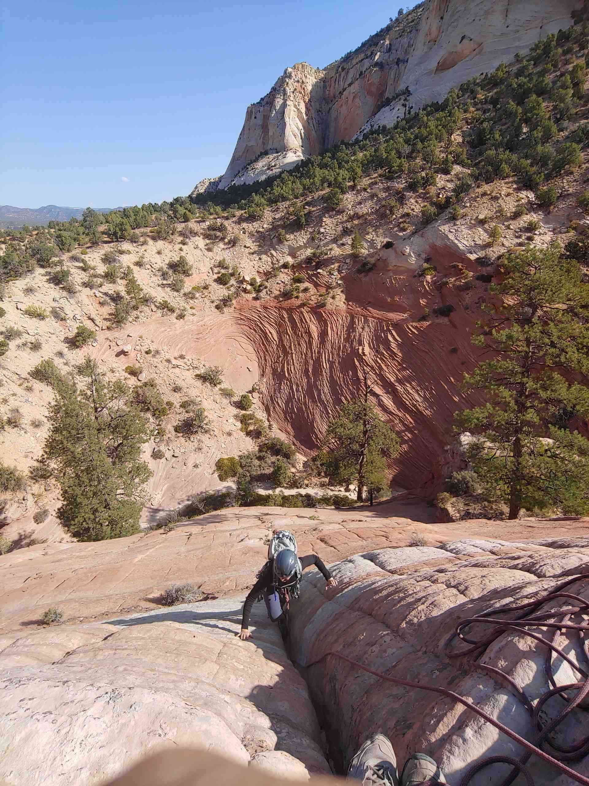 A person is climbing up a rocky cliff in the desert