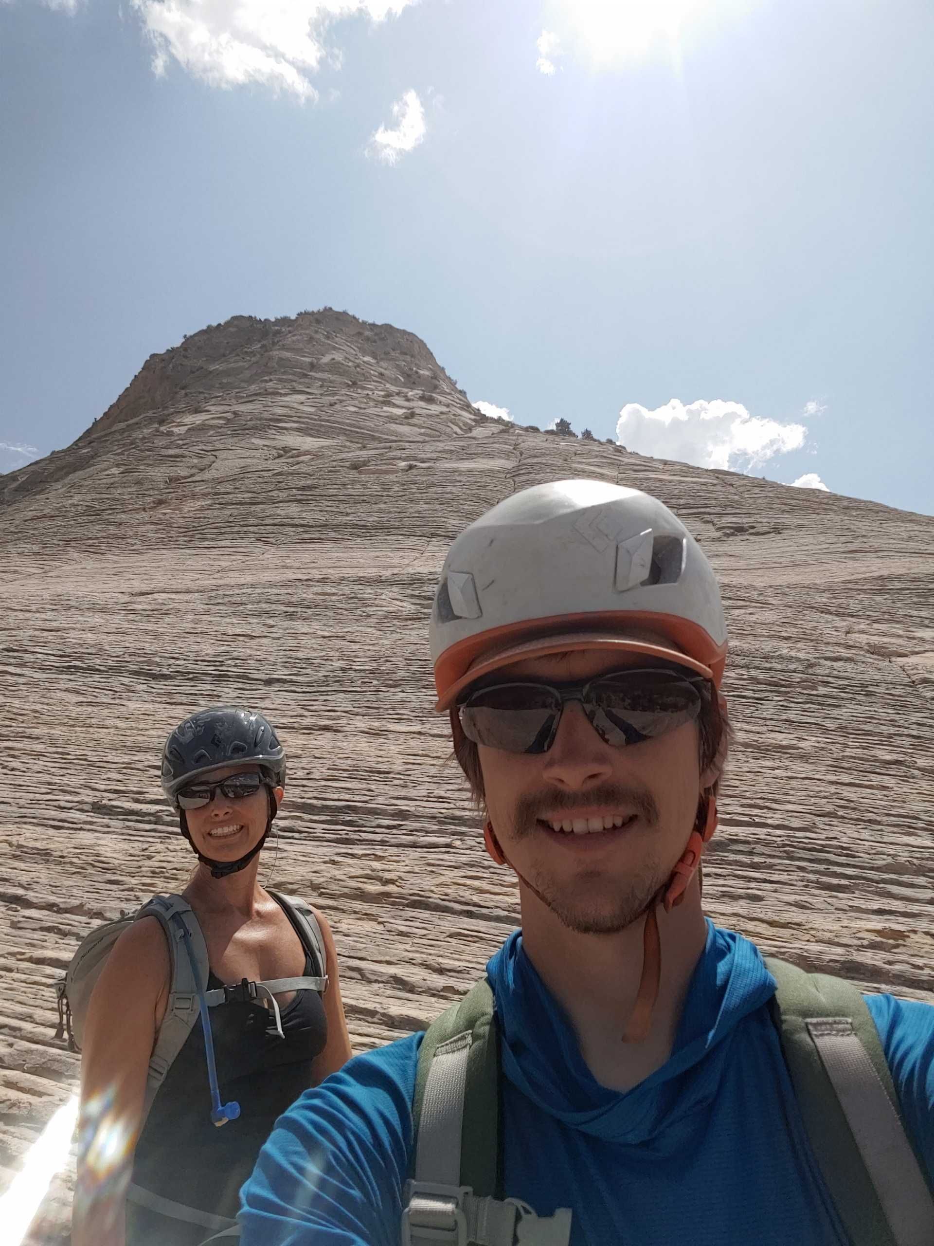 A man and a woman are taking a selfie in front of a mountain.
