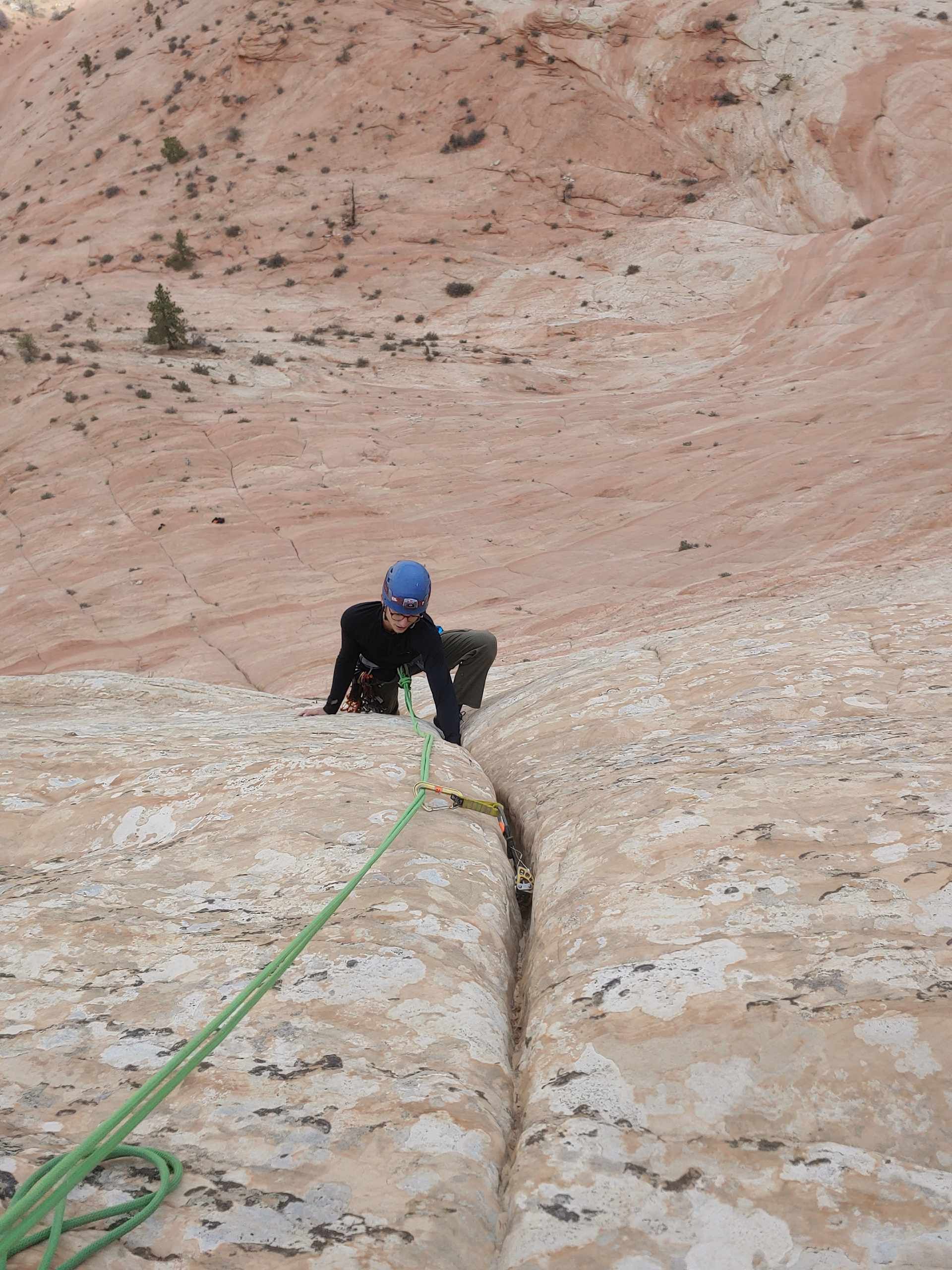 A person wearing a blue helmet is climbing a rock wall