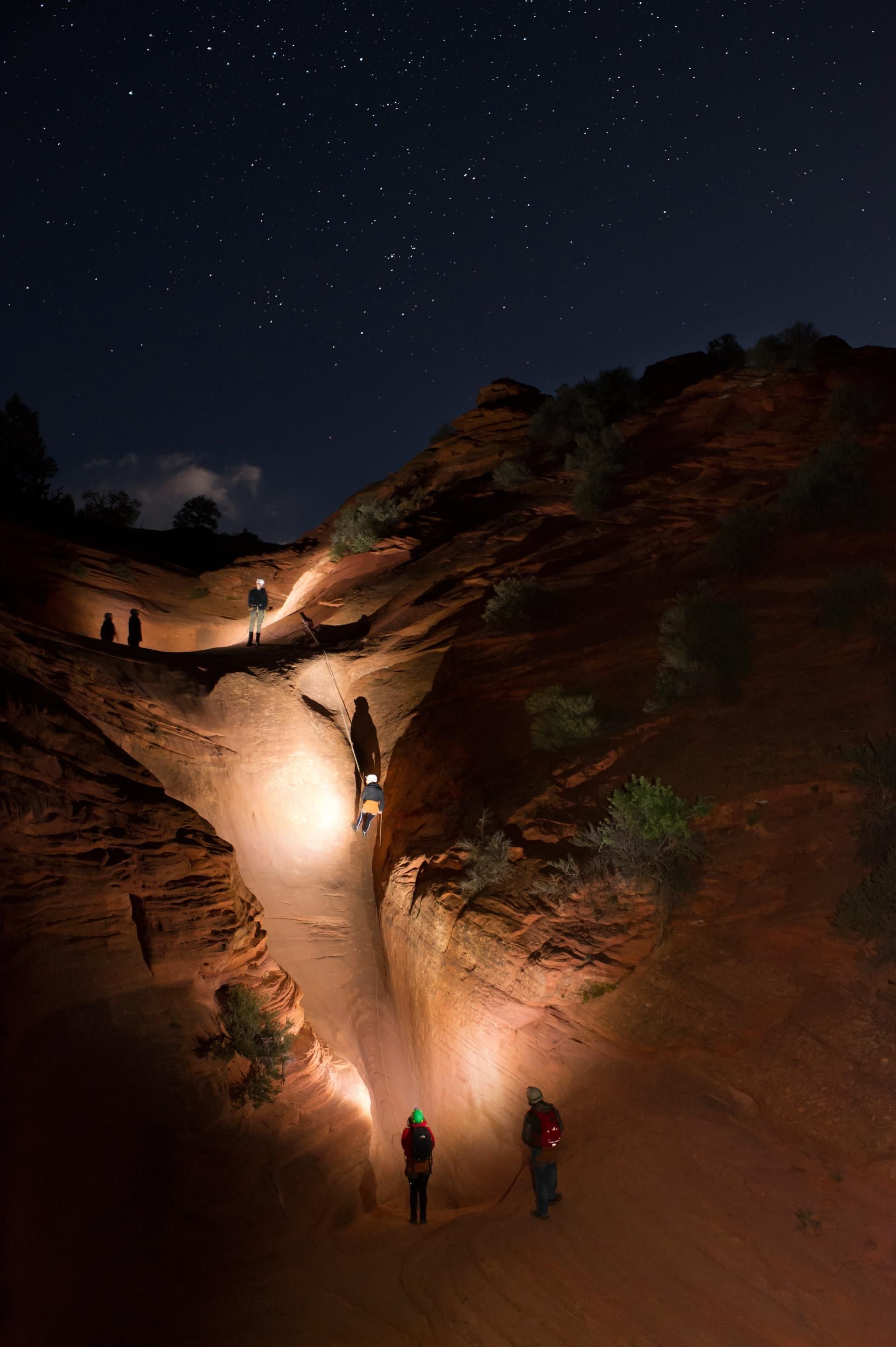 A group of people are walking up a hill at night