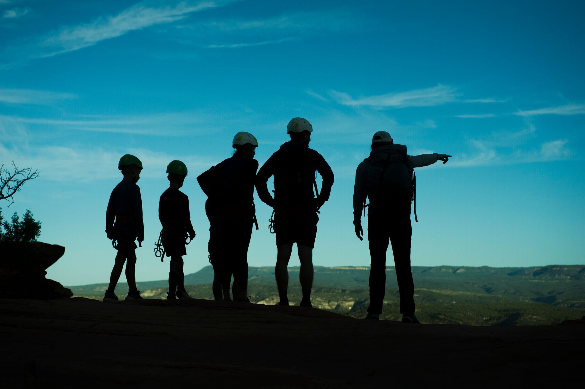 Silhouettes of people looking over a canyon at sunset