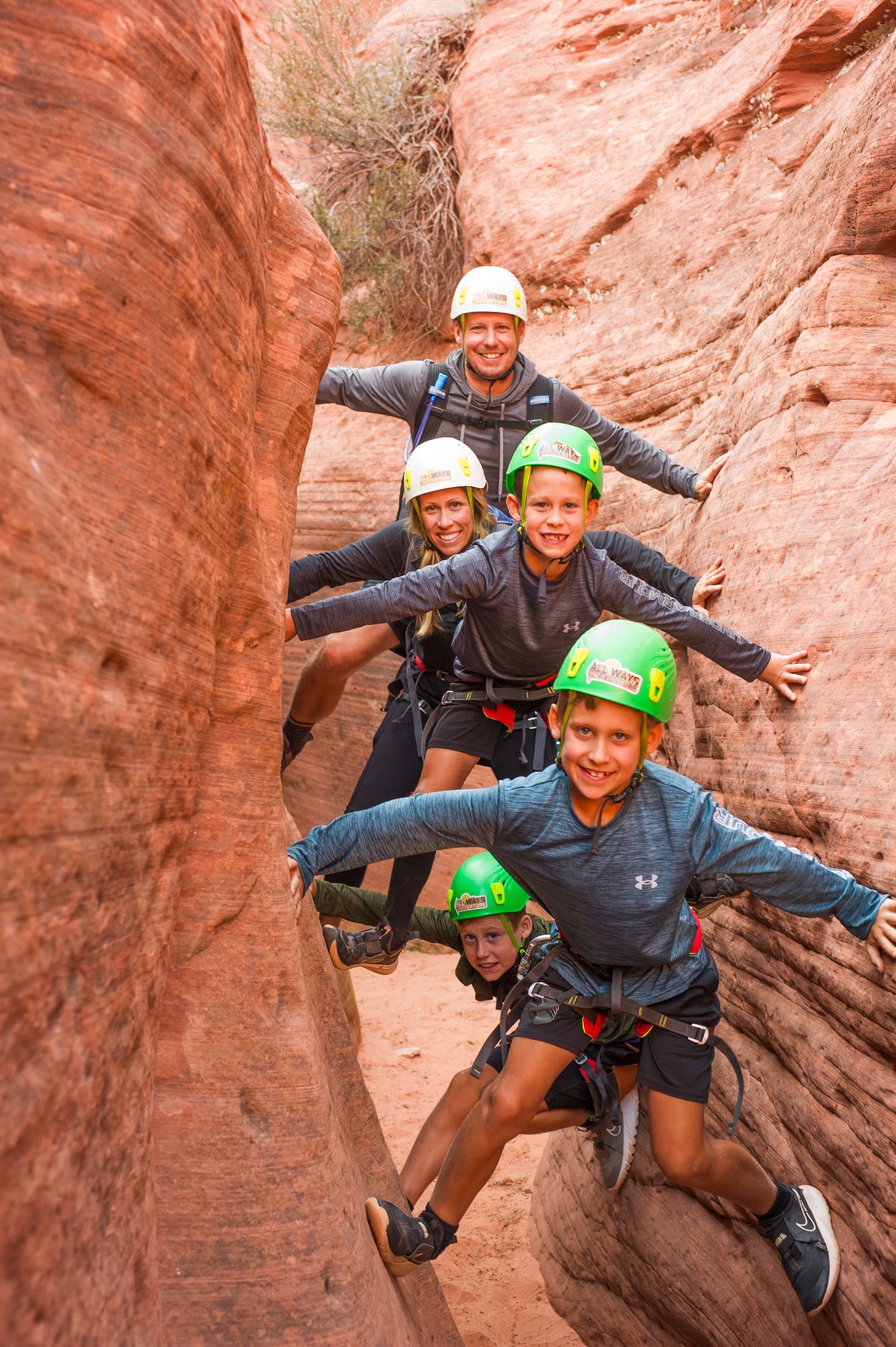 A group of people wearing helmets are climbing up a rock wall