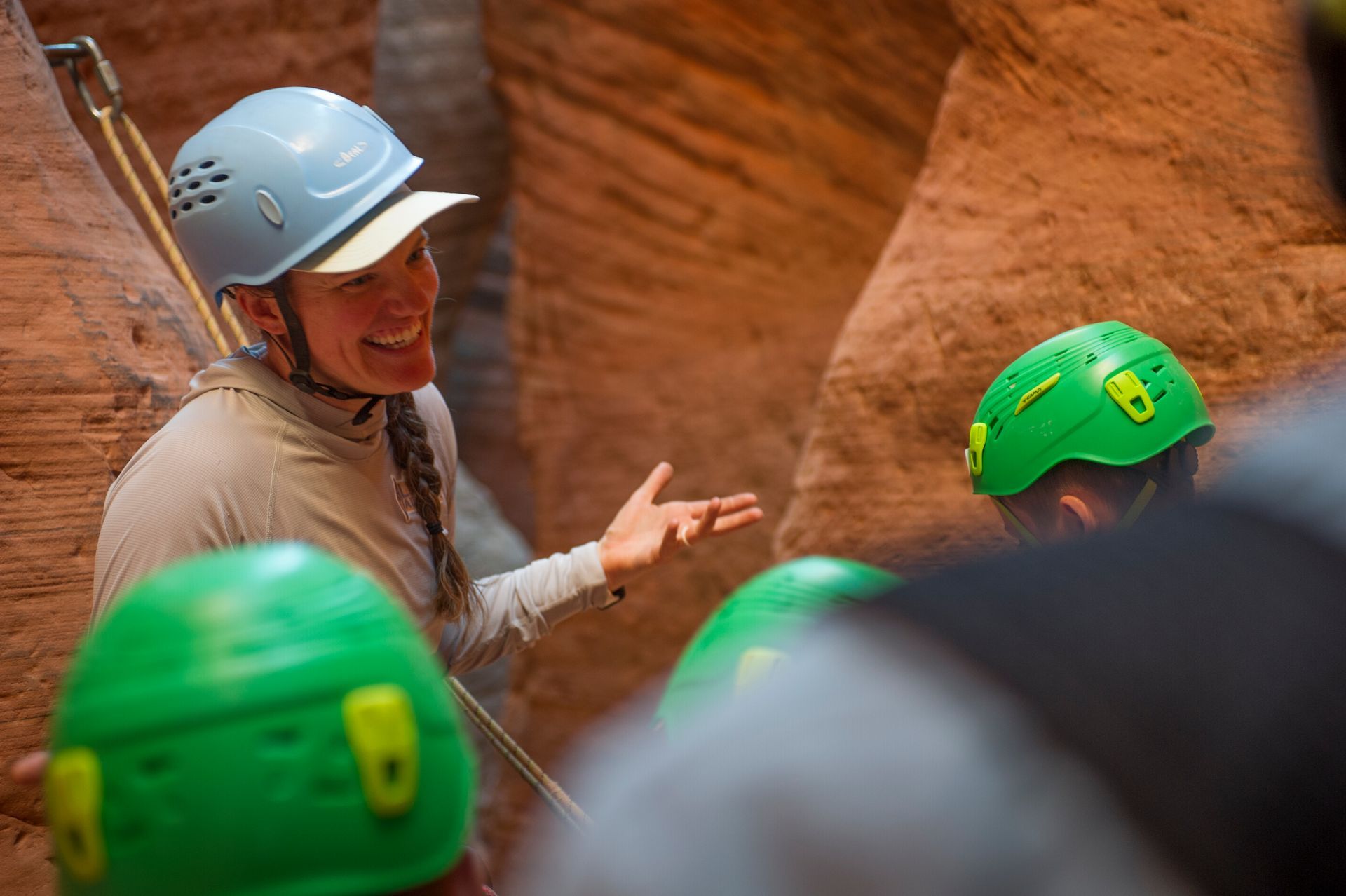 Jillian is smiling and making a gesture with her hands in a slot canyon