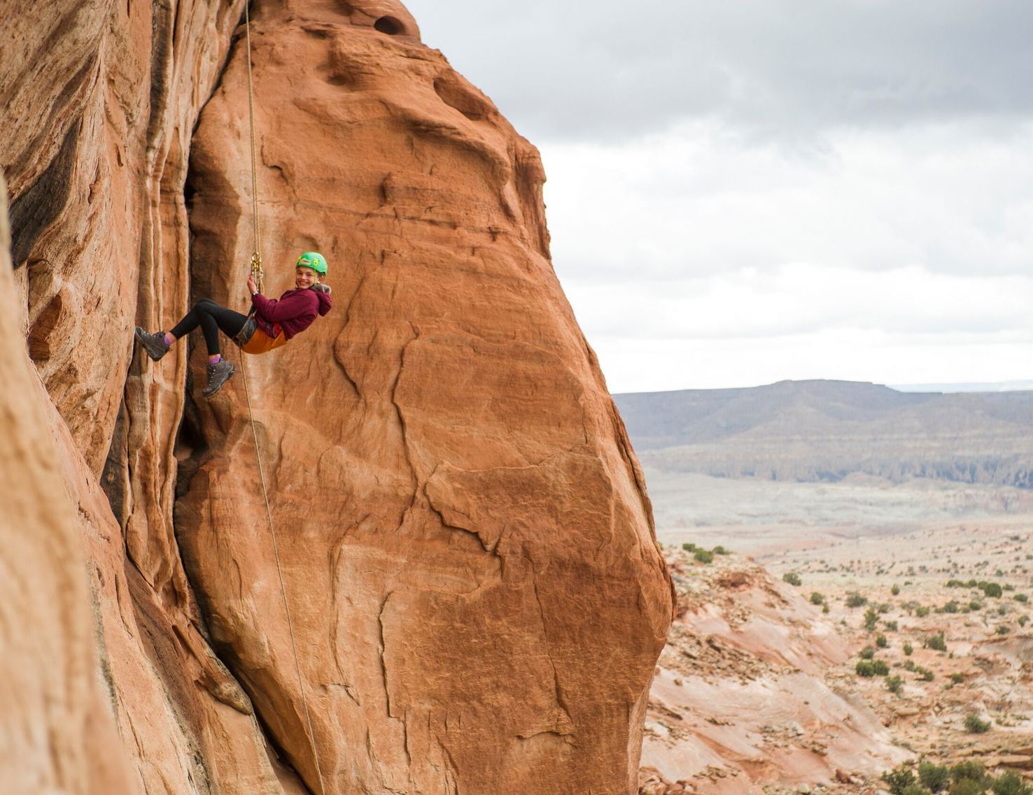 A person is sitting on a rock with their feet on a rope.