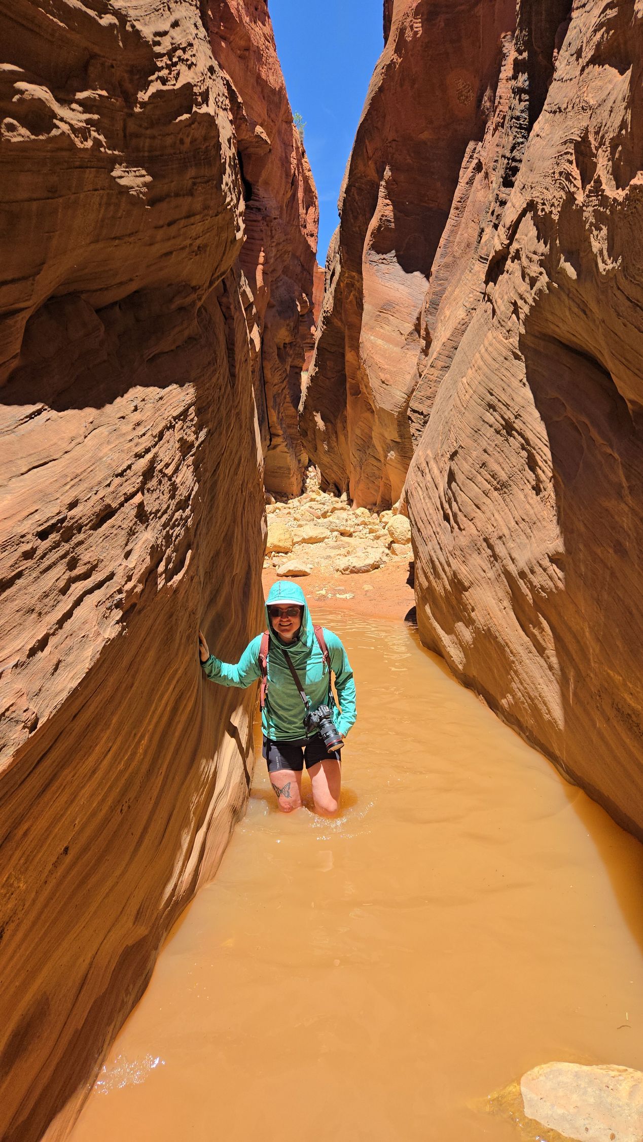 A person is standing in the middle of a canyon in the water.