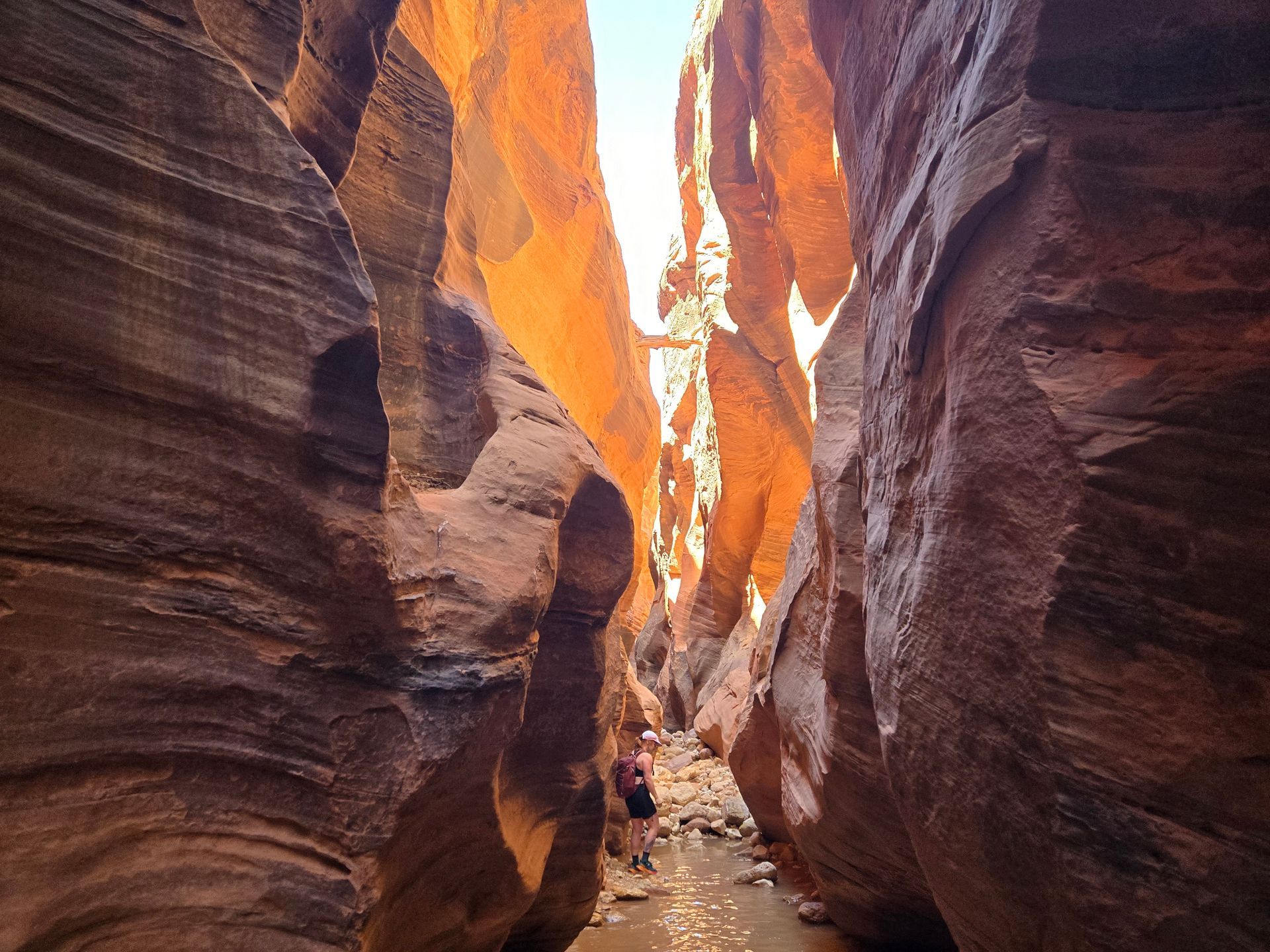 A man with a blue backpack is walking down a rocky trail