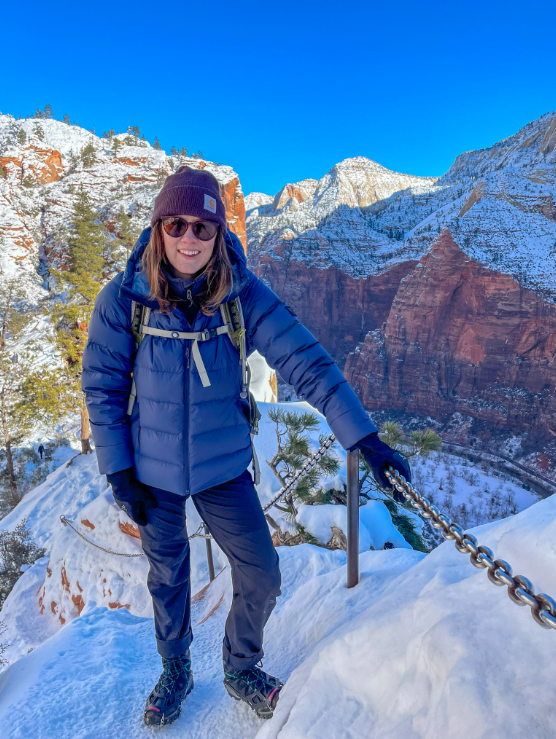 a woman holding onto a chain that's on a hike on the mountain