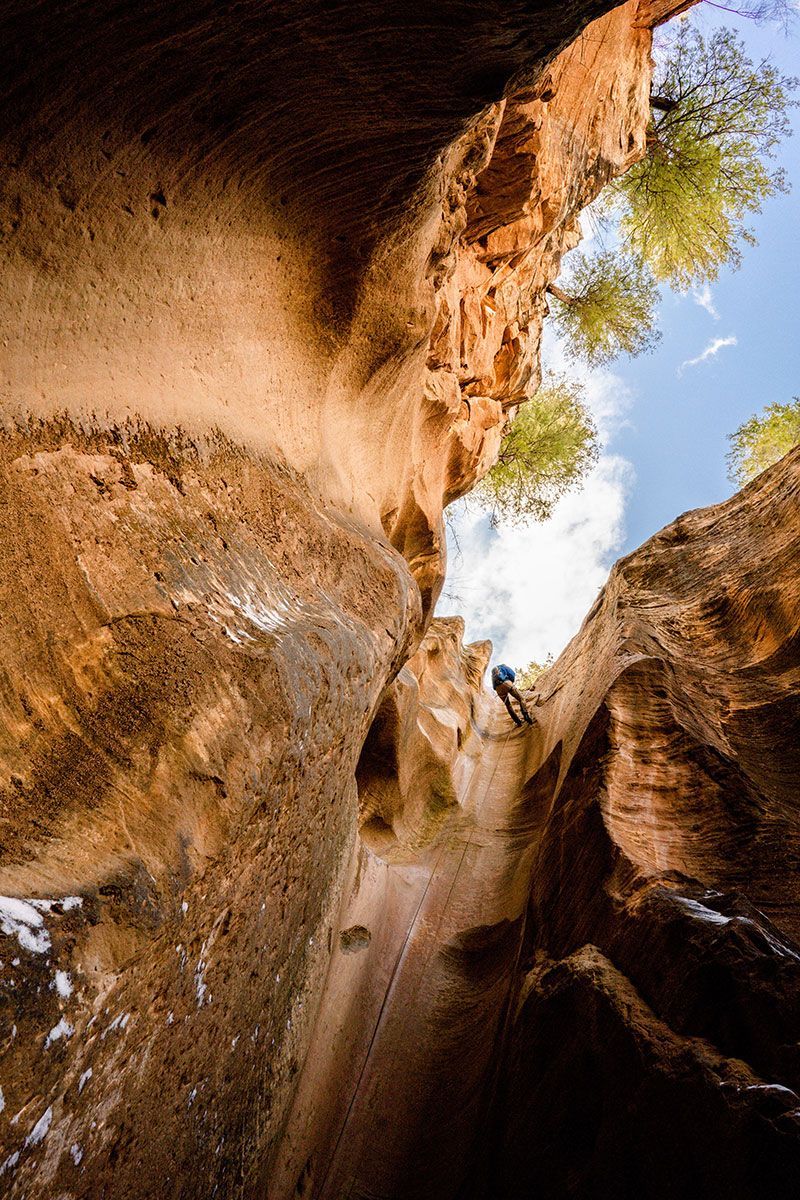 A person is climbing up a cliff in a canyon