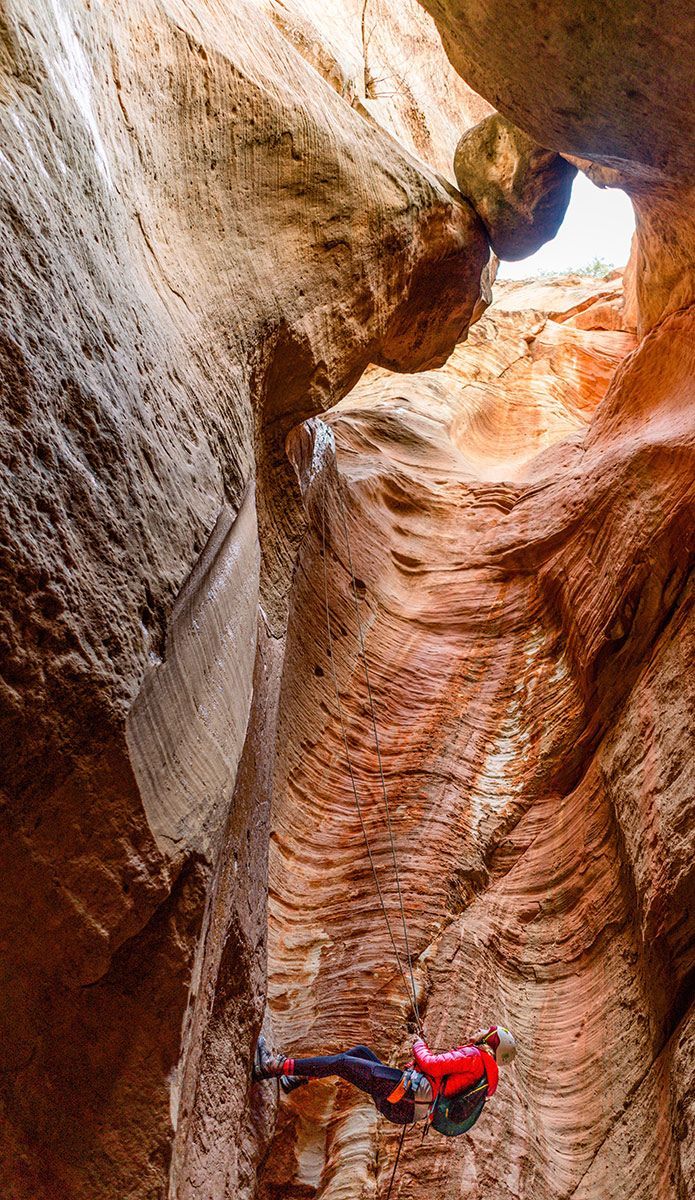 A person is climbing up a rock wall in a canyon.